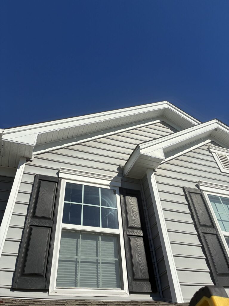 Gables of a gray house in daylight, with the white light track hidden along the white trim